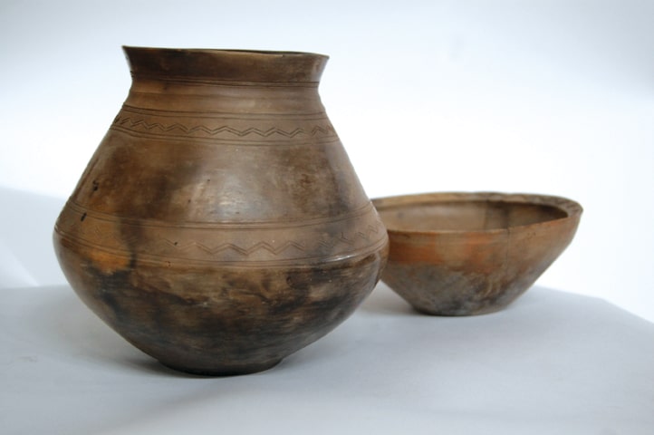 Funerary urn, biconical, surmounted by a bowl-lid, with decoration on the rim